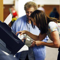 Malinda Bills, front, and Beverly Noorda set up a voting machine at Sandy Elementary School in Sandy, Monday, Nov. 7, 2011.