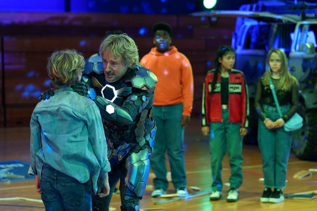 owen wilson in iron man-esque armor, comforting a blonde child