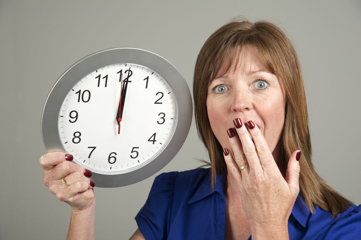 Woman with surprised expression holding a clock