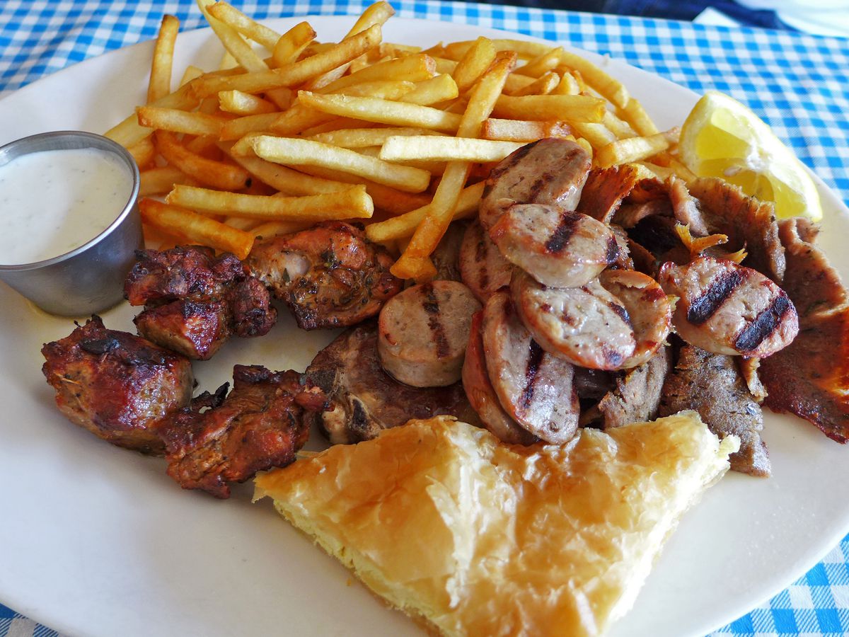 A platter with various kinds of chunked meat along with french fries.