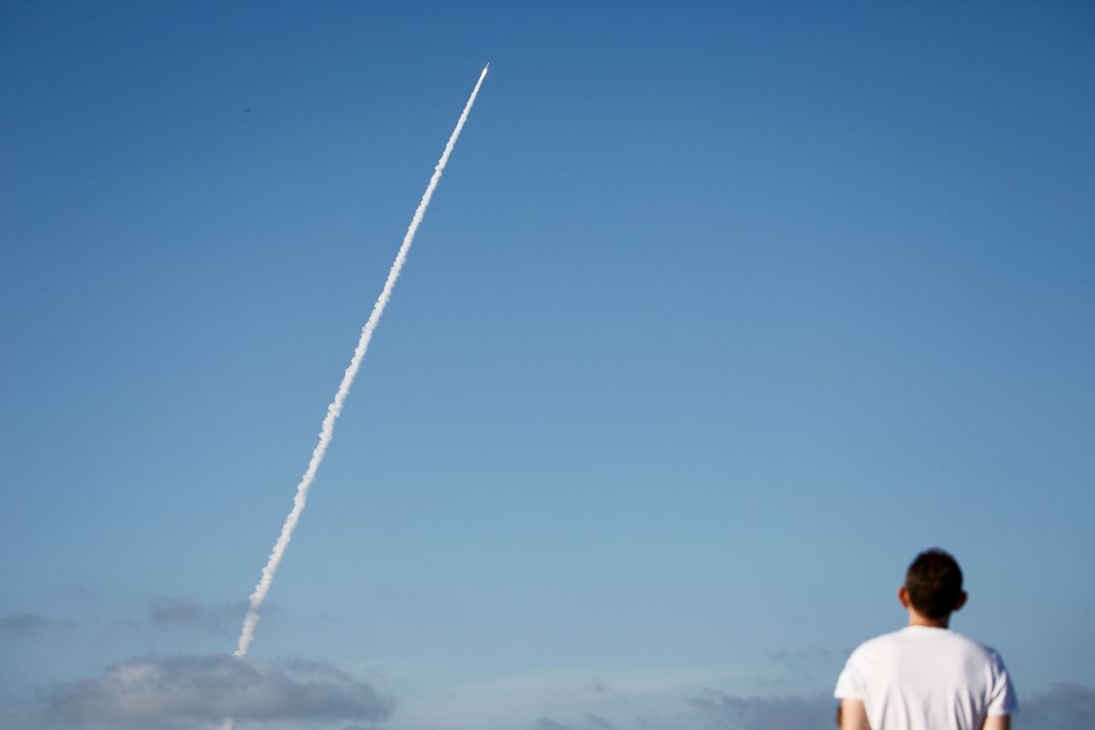 A person watches the vapor trail of a rocket launch.