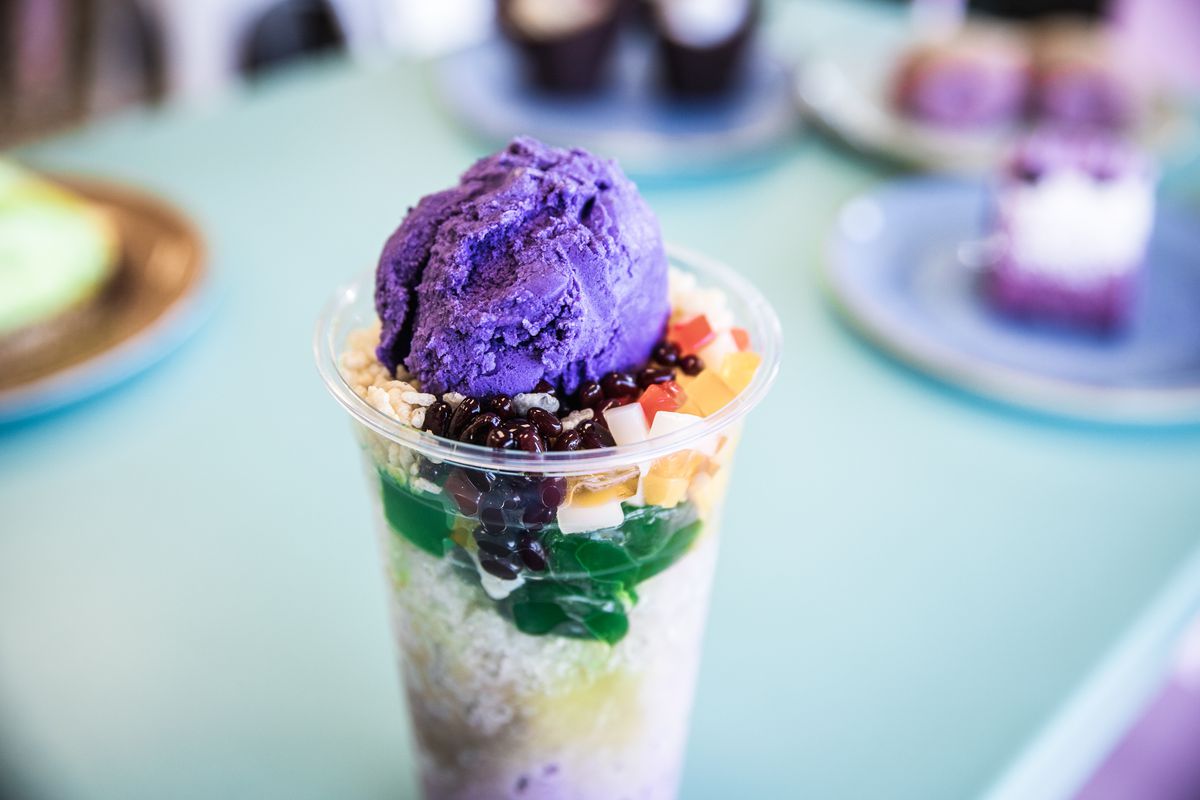 A clear plastic cup filled with halo-halo, a Filipino dessert with purple ube ice cream, sweet bans, jelly, and more.