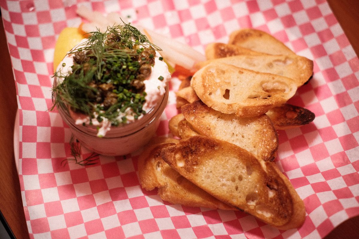 Smoked trout dip and grilled baguette on red and white checkered paper. 