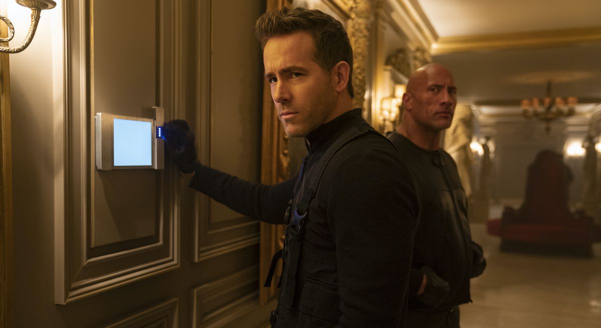 Ryan Reynolds smugly messes with an electronic alarm and Dwayne Johnson lurks in the background in Red Notice