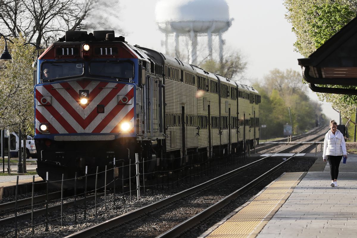 A Metra train arrives as a woman walks on the platform at the Glenview Amtrak/Metra Station. 
