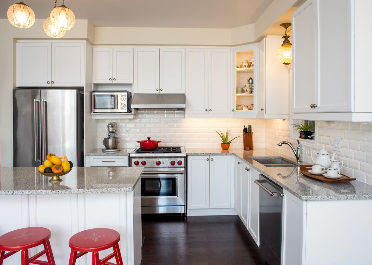 white kitchen with red accents and red stools