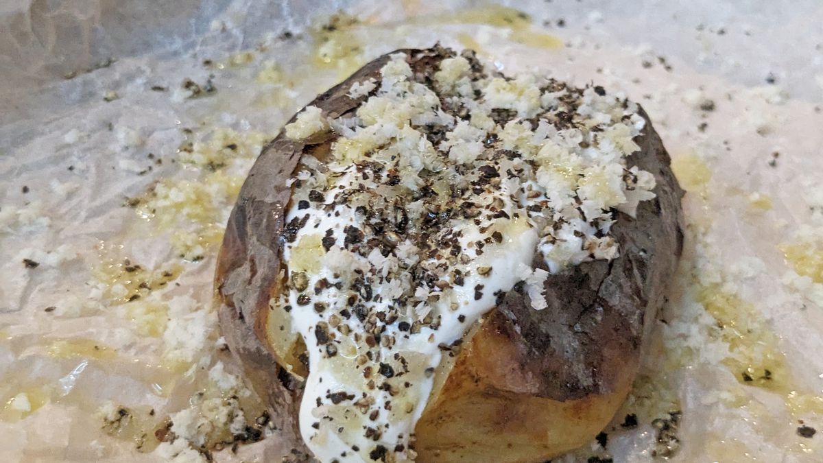 A baked potato oozing white creme fraiche.