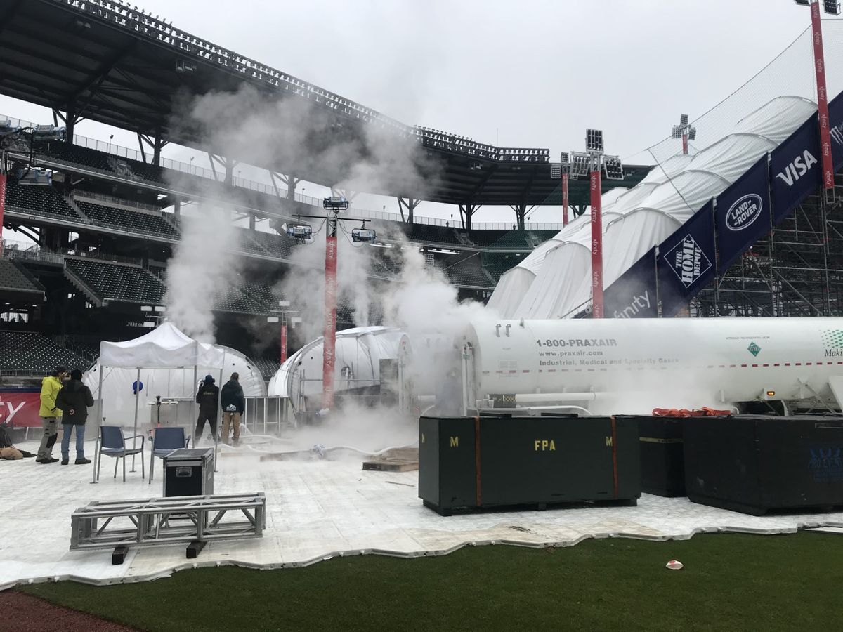 A snow-blowing machine in the middle of a baseball park. 