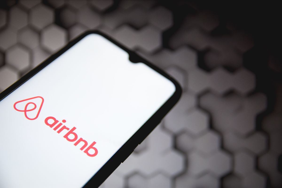 Airbnb logo seen displayed on a smartphone screen with a computer wallpaper in the background in Athens, Greece, on May 5, 2021.