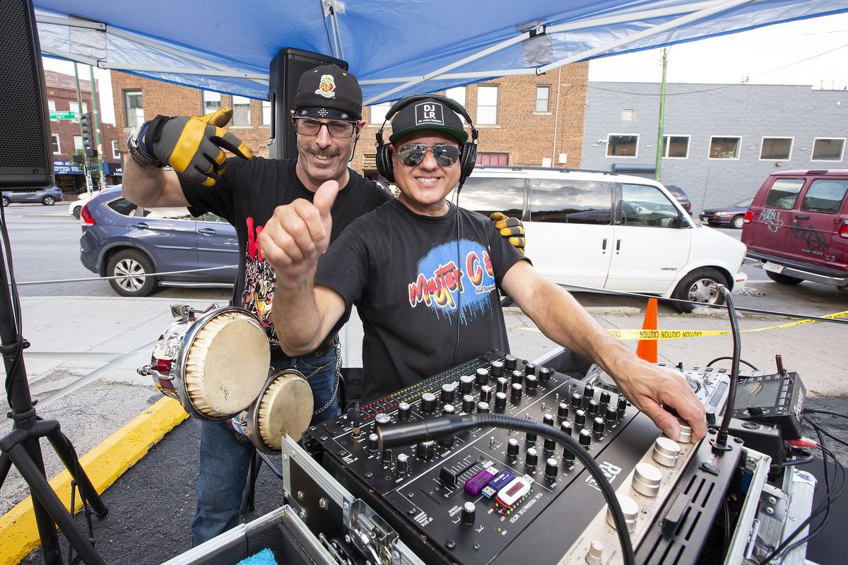 Two people smiling near a DJ deck.