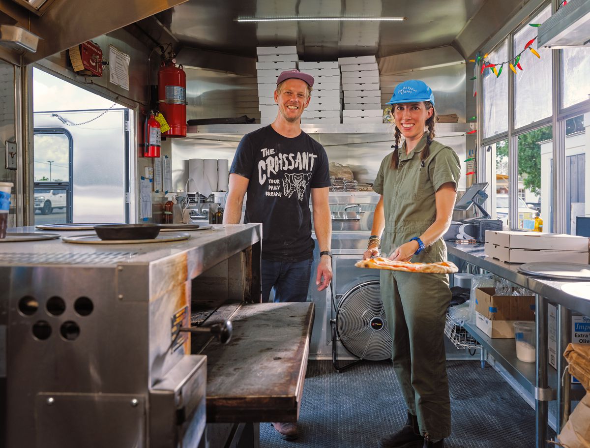 Two people in a food truck kitchen.