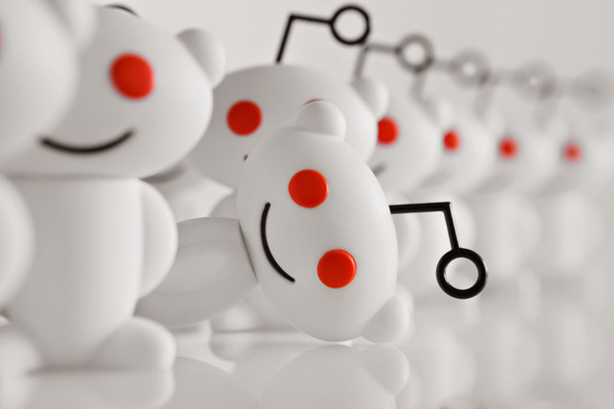 Artwork of Reddit snoos, with one peeking out from the crowd.