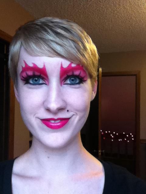 An author with pink eye makeup and long fake lashes, smiling at the camera.