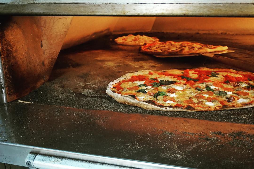 A pizza cooked in a brick oven.