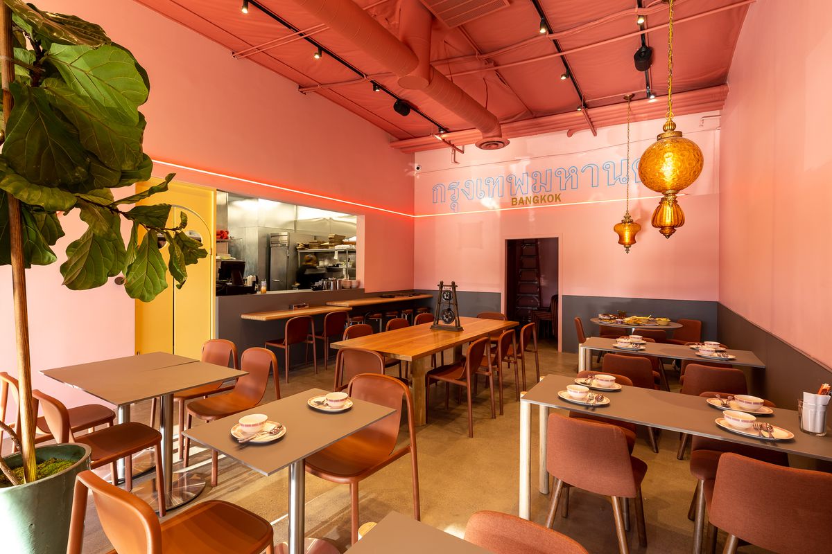 Dining room at Tuk Tuk Thai in West LA with orange hanging lights, greenery on the side, and modern furniture.