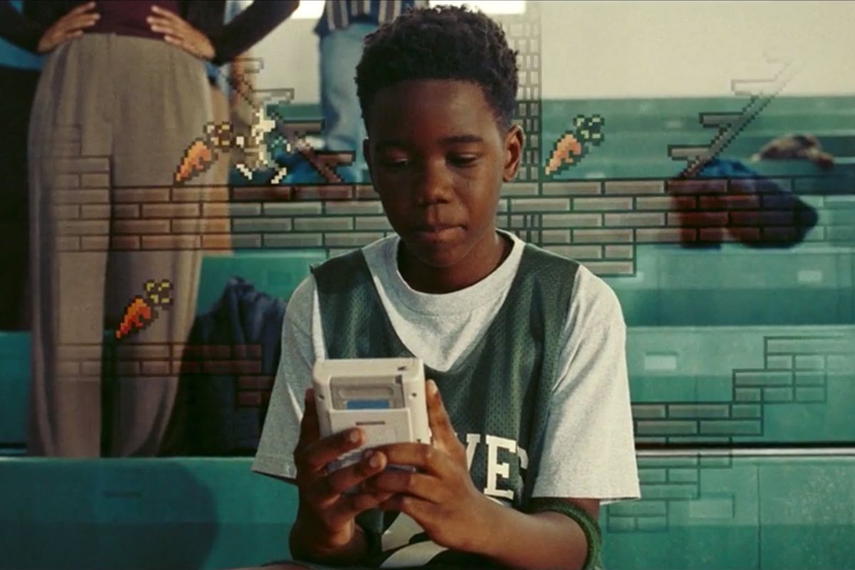 Young LeBron James plays a Game Boy in a still from Space Jam: A New Legacy