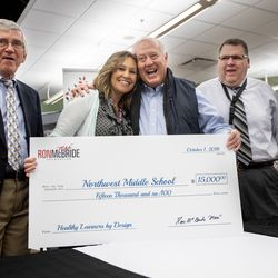 Dr. David M. Compton, executive director of the Ron McBride Foundation, principal Marissa Zuchetto, coach Ron McBride and Jon Goldhardt, executive director School Leadership and Performance stand with a giant check as the Ron McBride Foundation gives $15,000 to Northwest Middle School to support the Healthy Learners Initiative. on Monday, Oct. 8, 2018.