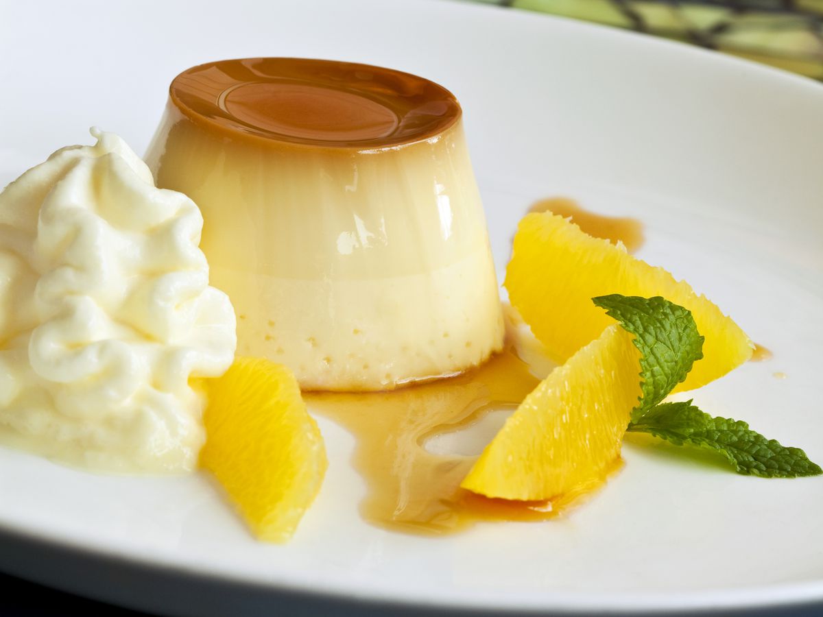 A yellow flan with fruit and whipped cream