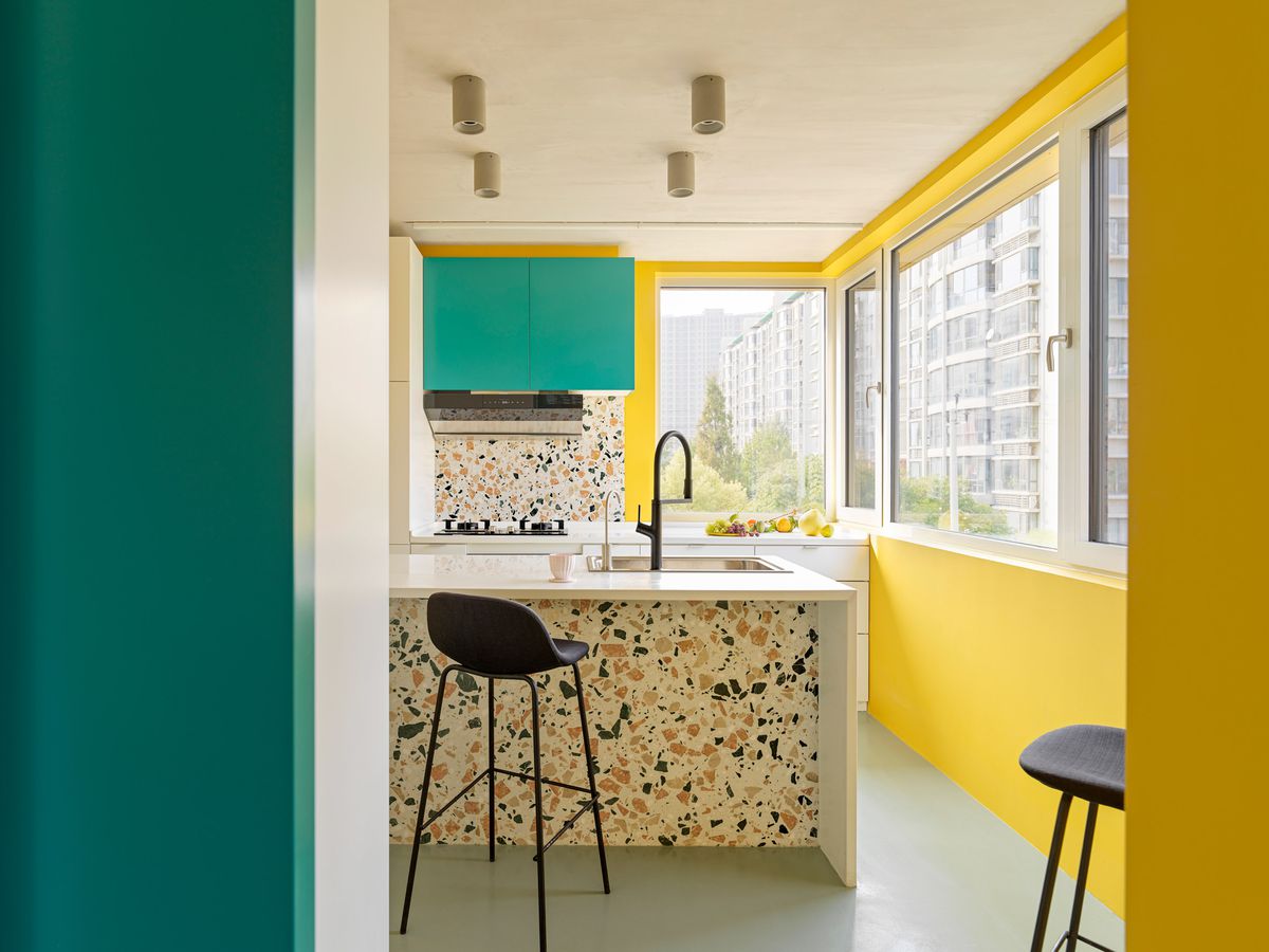 Kitchen with terrazzo backsplash, green cabinets, and yellow walls. 