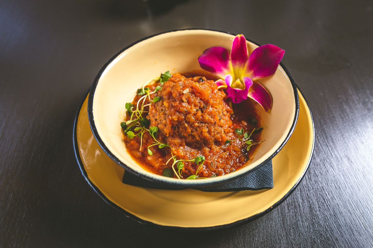 A bowl of rice covered in pepper sauce with a flower on top.