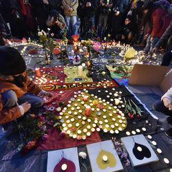People put candles on painted hearts with the Belgian colors to mourn for the victims at the place de la Bourse in the center of Brussels, Tuesday, March 22, 2016. Bombs exploded at the Brussels airport and one of the city's metro stations Tuesday, killing and wounding scores of people, as a European capital was again locked down amid heightened security threats. 