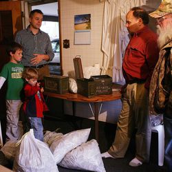 From left, Josh Ferrin (standing) and his sons Lincoln and Oliver, who recently closed on a new home, turn over bags of money and ammo boxes to Dennis and Kay Bangerter, sons of the former owner at the home in Bountiful Wednesday, May 18, 2011. Ferrin found the stash of money in the attic over the garage, two hours after he took ownership of the home.