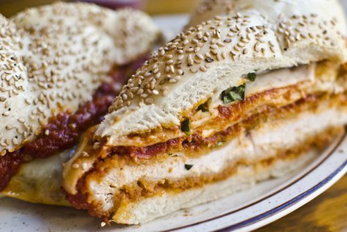 A sesame-studded bun loaded with chicken parmesan cut diagonally