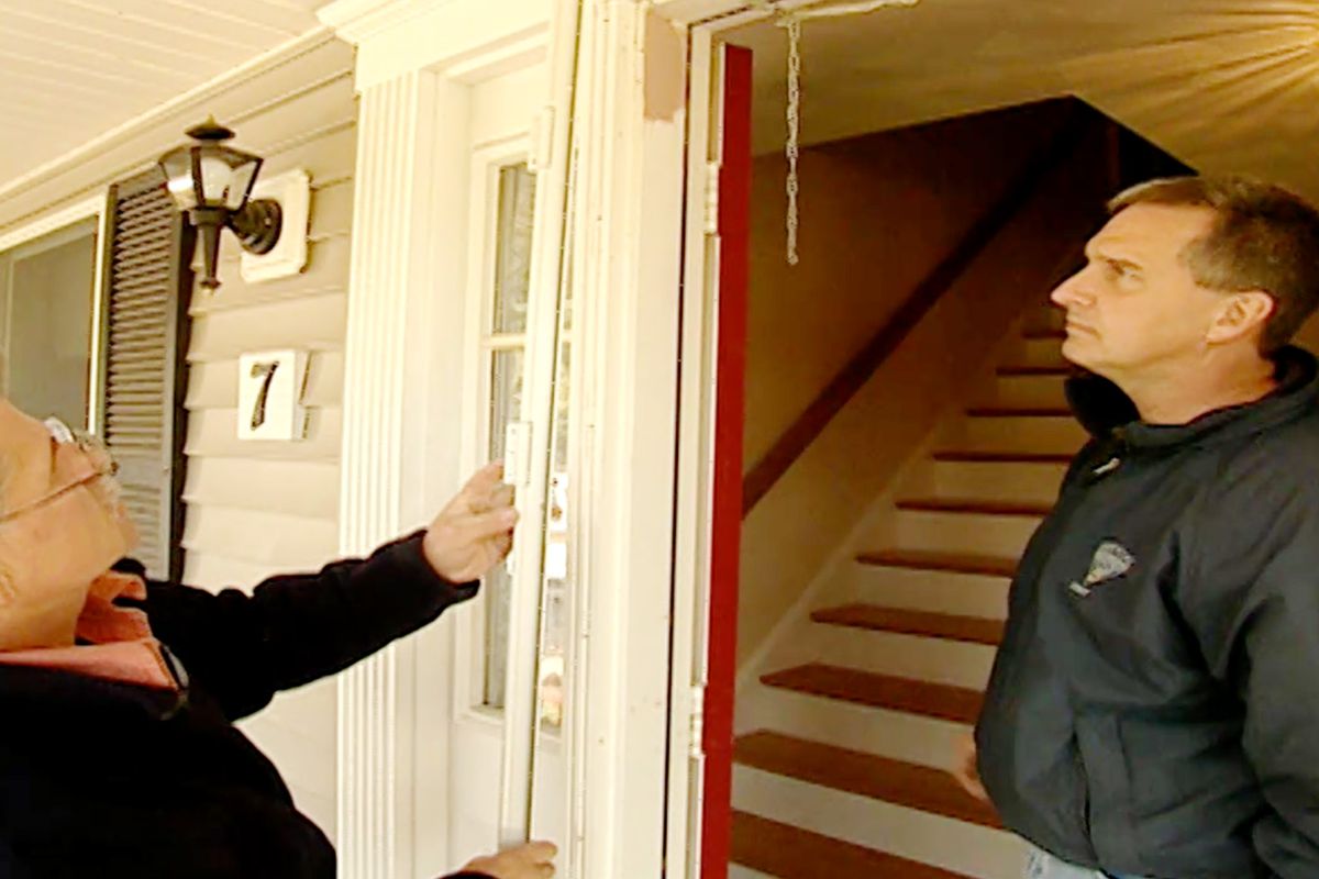 Two people inspect a frosted screen door.