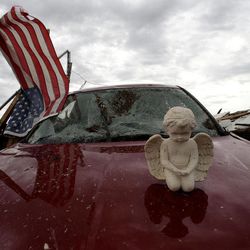 A concrete angel rests on a destropyed car in a tornado-ravaged neighborhood Tuesday, May 21, 2013, in Moore, Okla. A huge tornado roared through the Oklahoma City suburb Monday, flattening entire neighborhoods and destroying an elementary school with a direct blow as children and teachers huddled against winds. 
