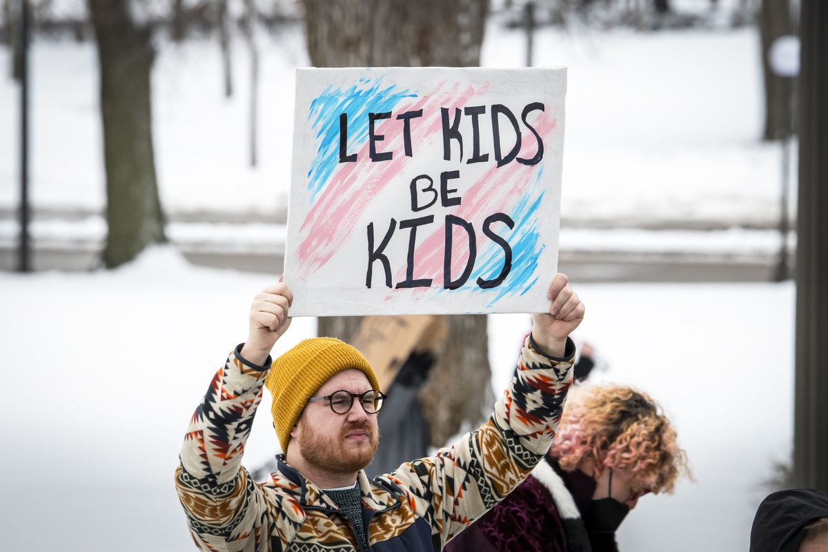 A protester holds up a sign that reads, “Let kids be kids.”