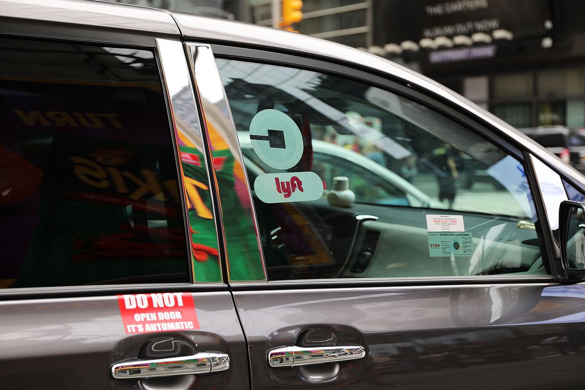 Ride-hailing car in NYC with both Uber and Lyft logos