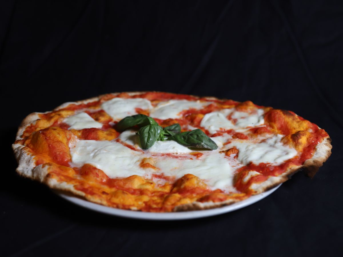 Thin margherita pizza on a black background