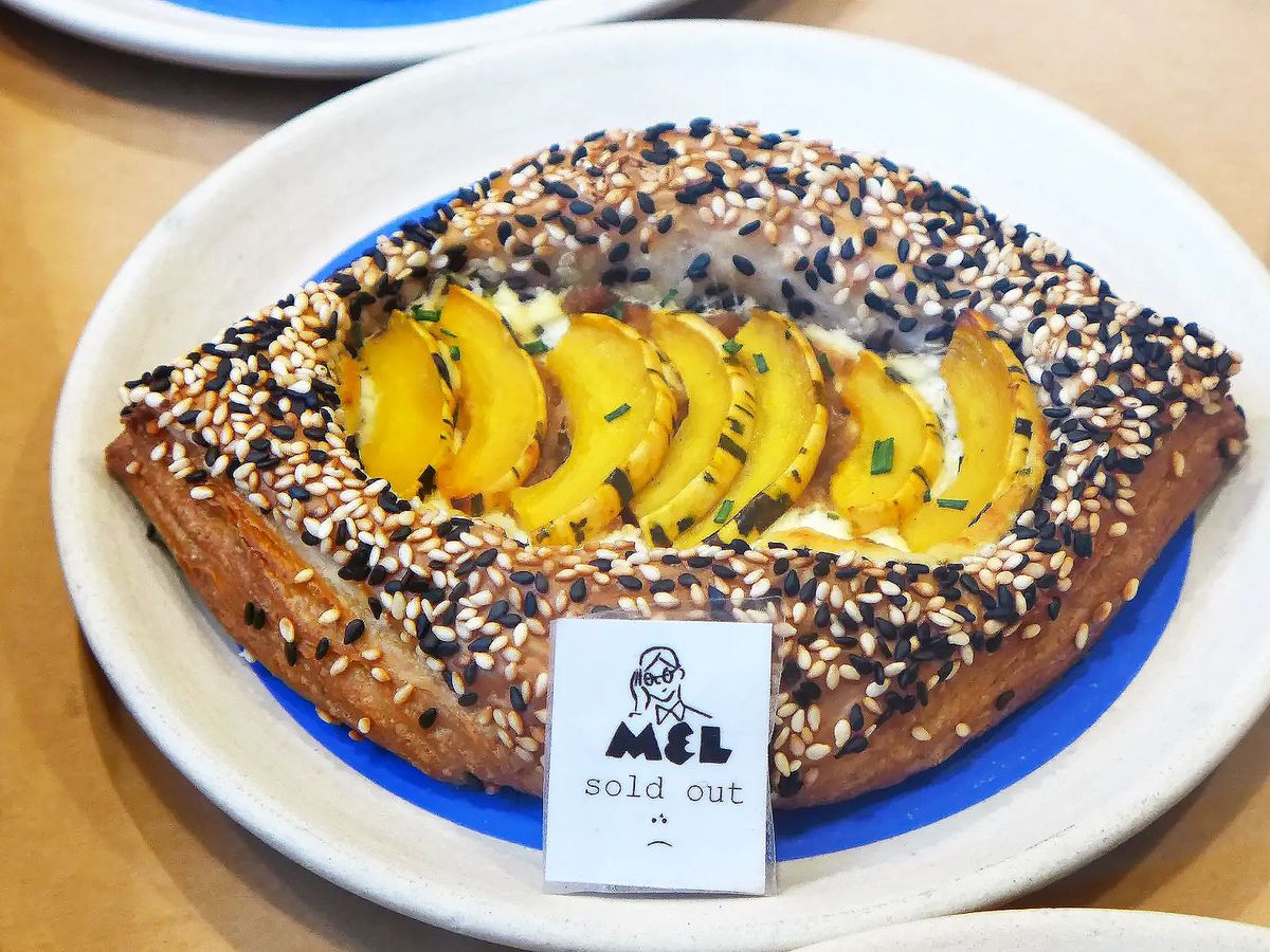 A savory danish with black and white sesame seeds and squash in the middle.