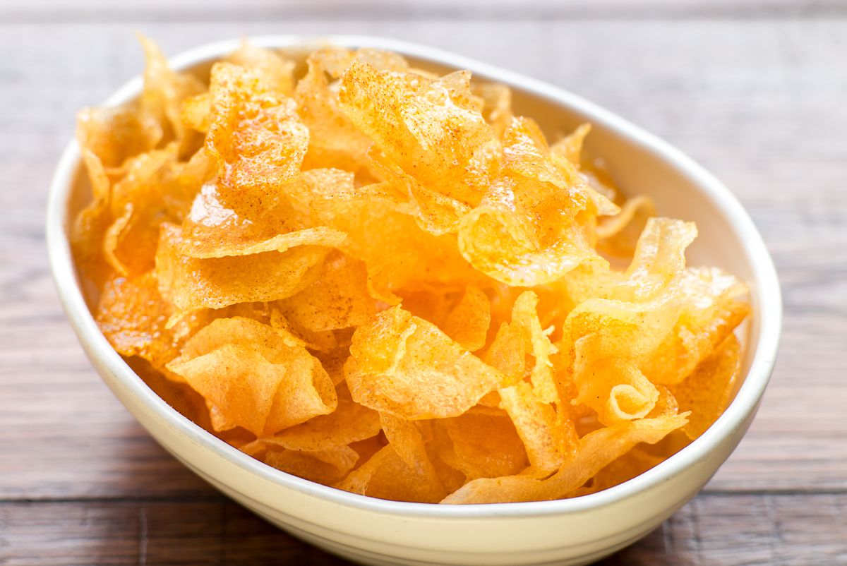 A heap of golden potato chips in a bowl, with presumably ice cream underneath.