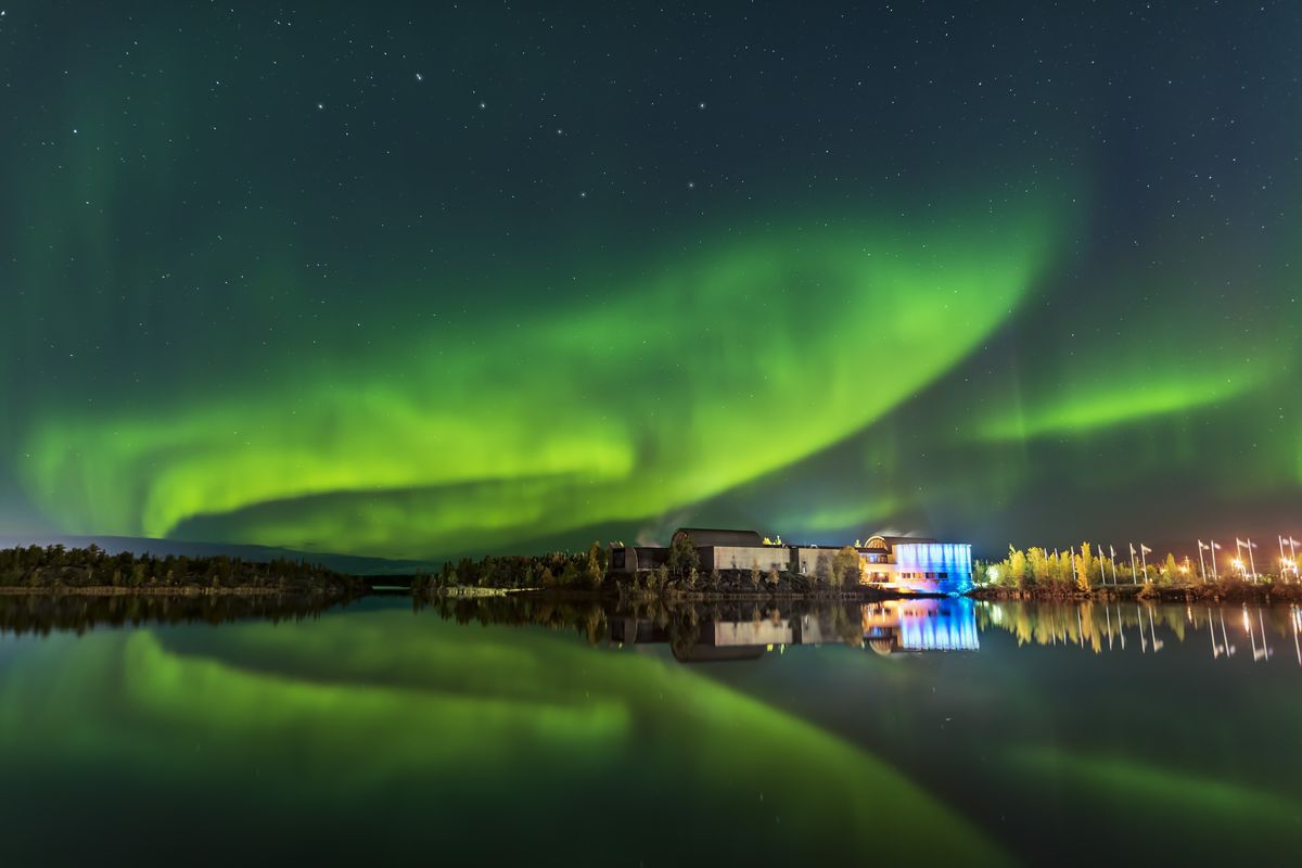 Aurora reflected in the calm waters of Frame Lake and arching over the Prince of Wales Museum in Yellowknife, Northwest Territories, Canada, on September 5, 2019.