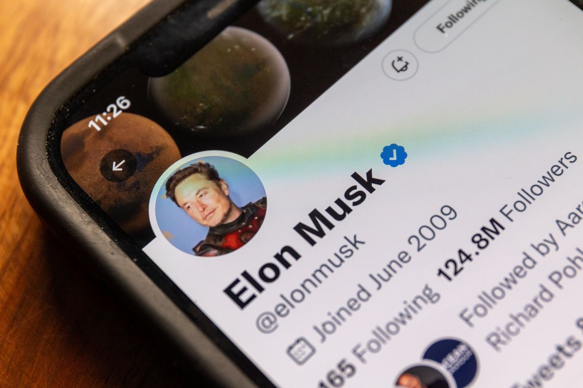 A photo of a phone on a desk with a close-up on Elon Musk’s Twitter account