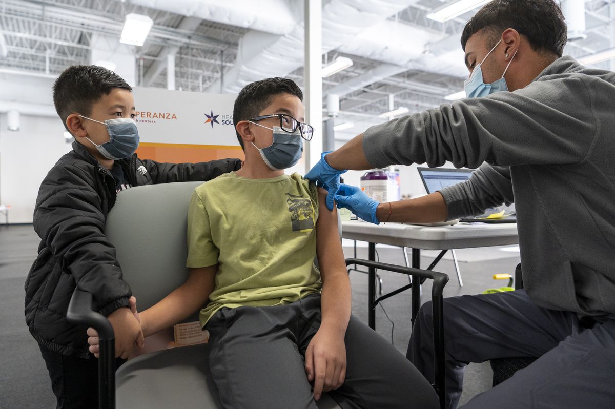 Enzo Garcia, 6 (left), holds the hand of his 9-year-old brother, Dante Garcia, while a medical assistant at Esperanza Health Centers administers a dose of the the Pfizer-BioNTech COVID-19 vaccine at the South Side vaccination site, Wednesday afternoon, Nov. 4, 2021.