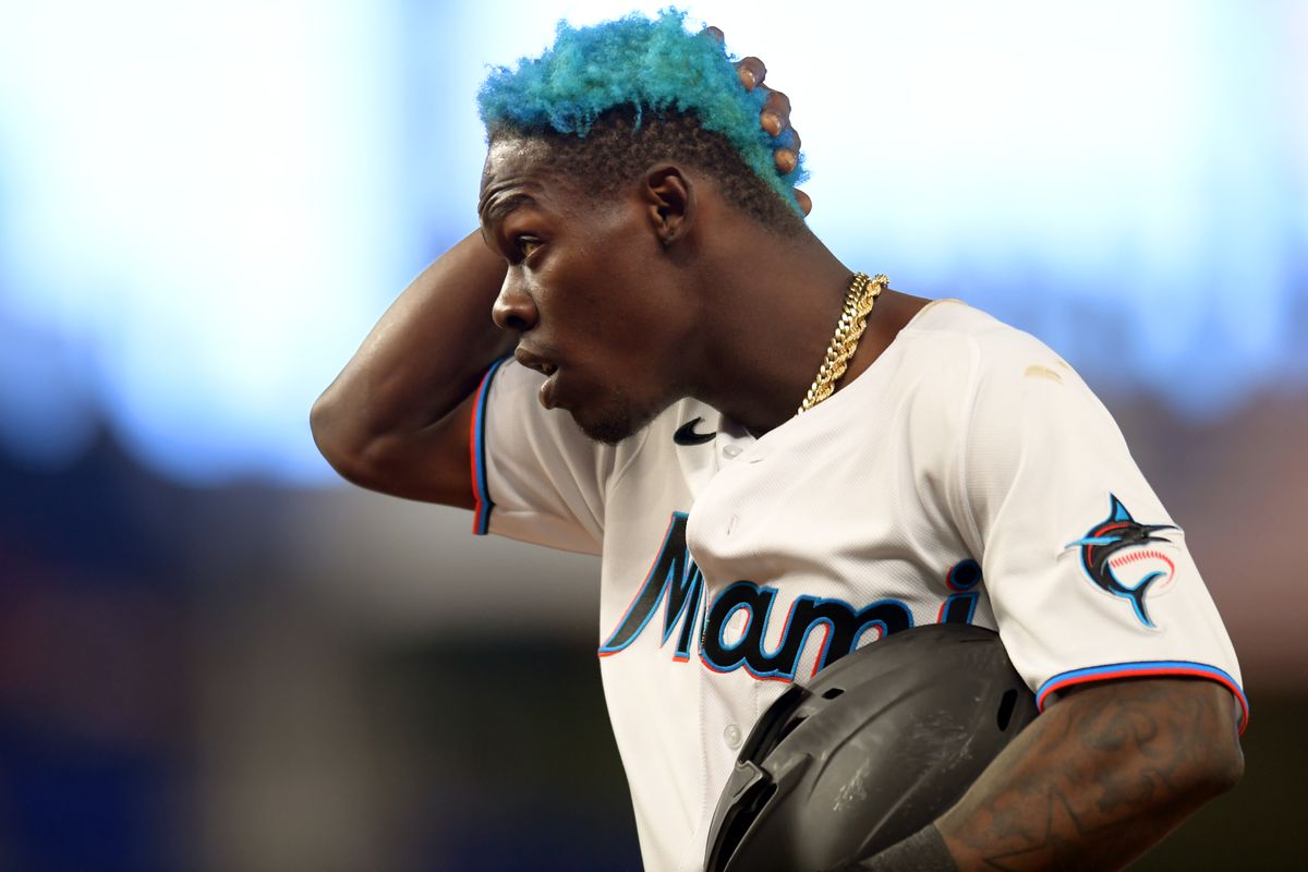 Jazz Chisholm takes his batting helmet off and runs his hand through his neon blue, Marlin themed hair while looking into the distance