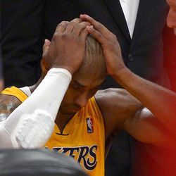 Los Angeles Lakers guard Kobe Bryant puts his head in his hands after being injured during the second half of their NBA basketball game against the Golden State Warriors, Friday, April 12, 2013, in Los Angeles. The Lakers won 118-116. 