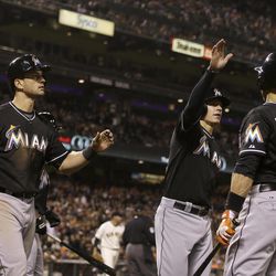 Miami Marlins' Justin Ruggiano, left, and Derek Dietrich, center, celebrate after both scored with Placido Polanco (30) against the San Francisco Giants during the eighth inning of a baseball game in San Francisco, Thursday, June 20, 2013. 