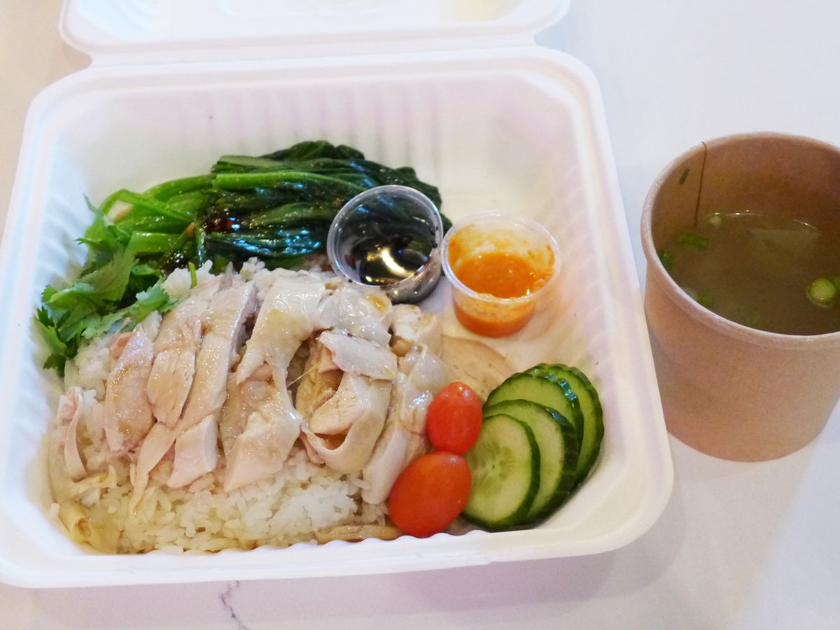 Pale slice chicken on rice served in a white styrofoam container.