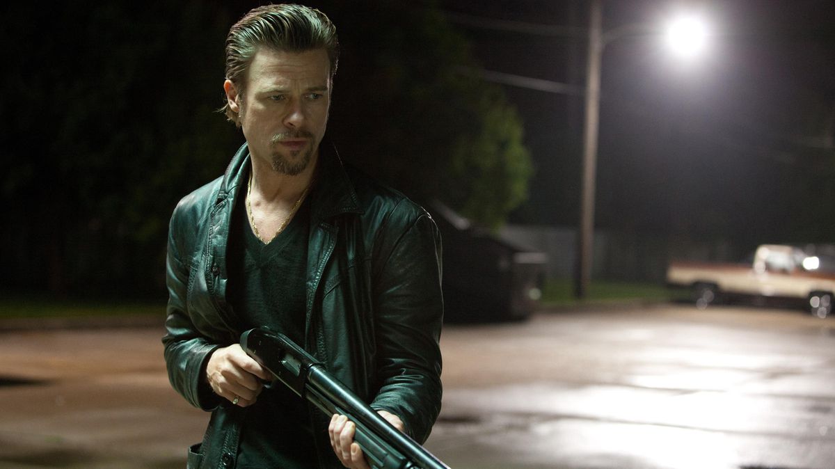 Bradas Pittas skaisčiais plaukais laiko šautuvą filme Killing Them Softly