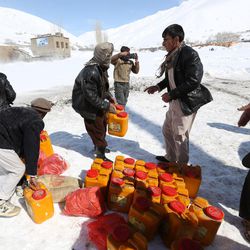 Survivors receive food donations near the site of an avalanche in the Paryan district of Panjshir province, north of Kabul, Afghanistan, Friday, Feb. 27, 2015. The death toll from severe weather that caused avalanches and flooding across much of Afghanistan has jumped to more than 200 people, and the number is expected to climb with cold weather and difficult conditions hampering rescue efforts, relief workers and U.N. officials said Friday. 