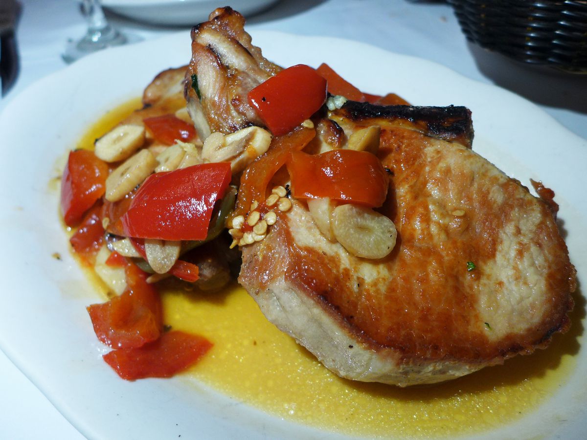 A pair of browned pork chops heaped with sweet and hot pickled peppers...