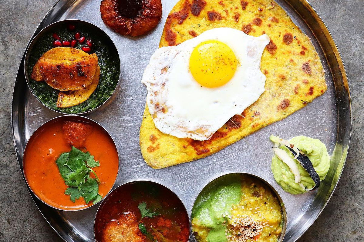 a morning thali spread with crispy carrot paratha and a fried egg