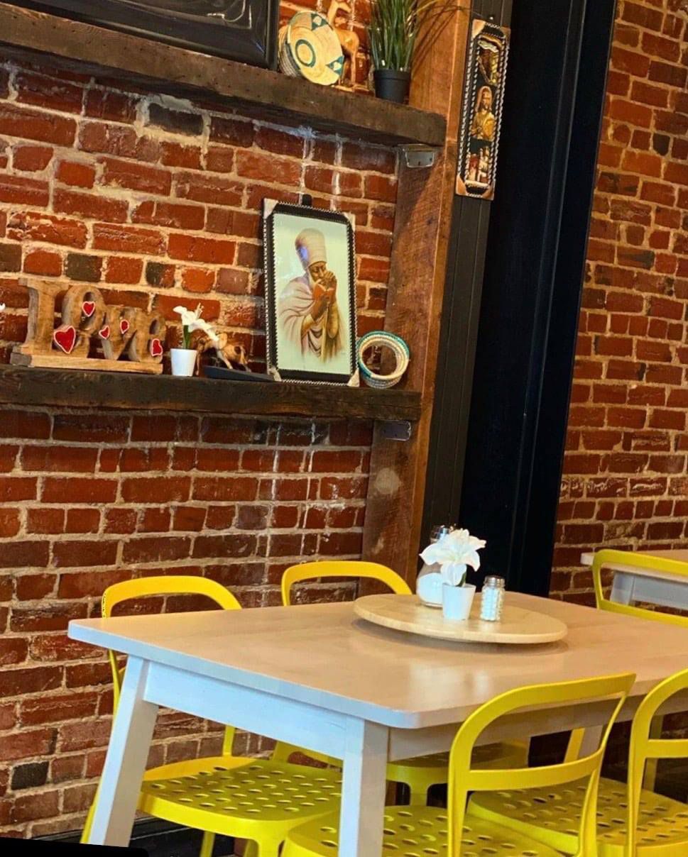 bright yellow dining chairs around a rectangular table in a room with exposed brick walls at Family Ethiopian