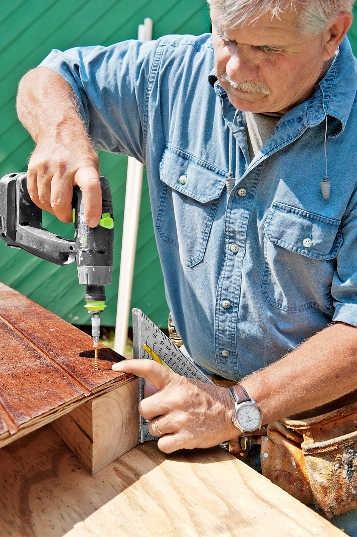 Tom Silva drilling a hole into a chicken coop