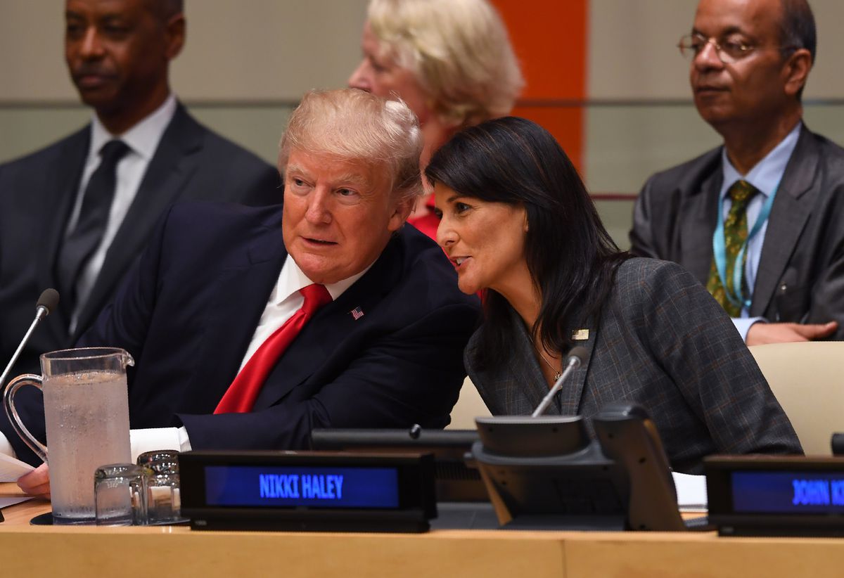Donald Trump and Nikki Haley speak while leaning toward each other.