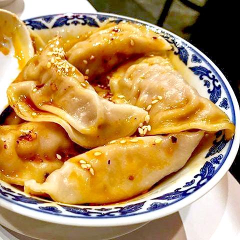 Dumplings in a bowl dressed with red chile oil. 