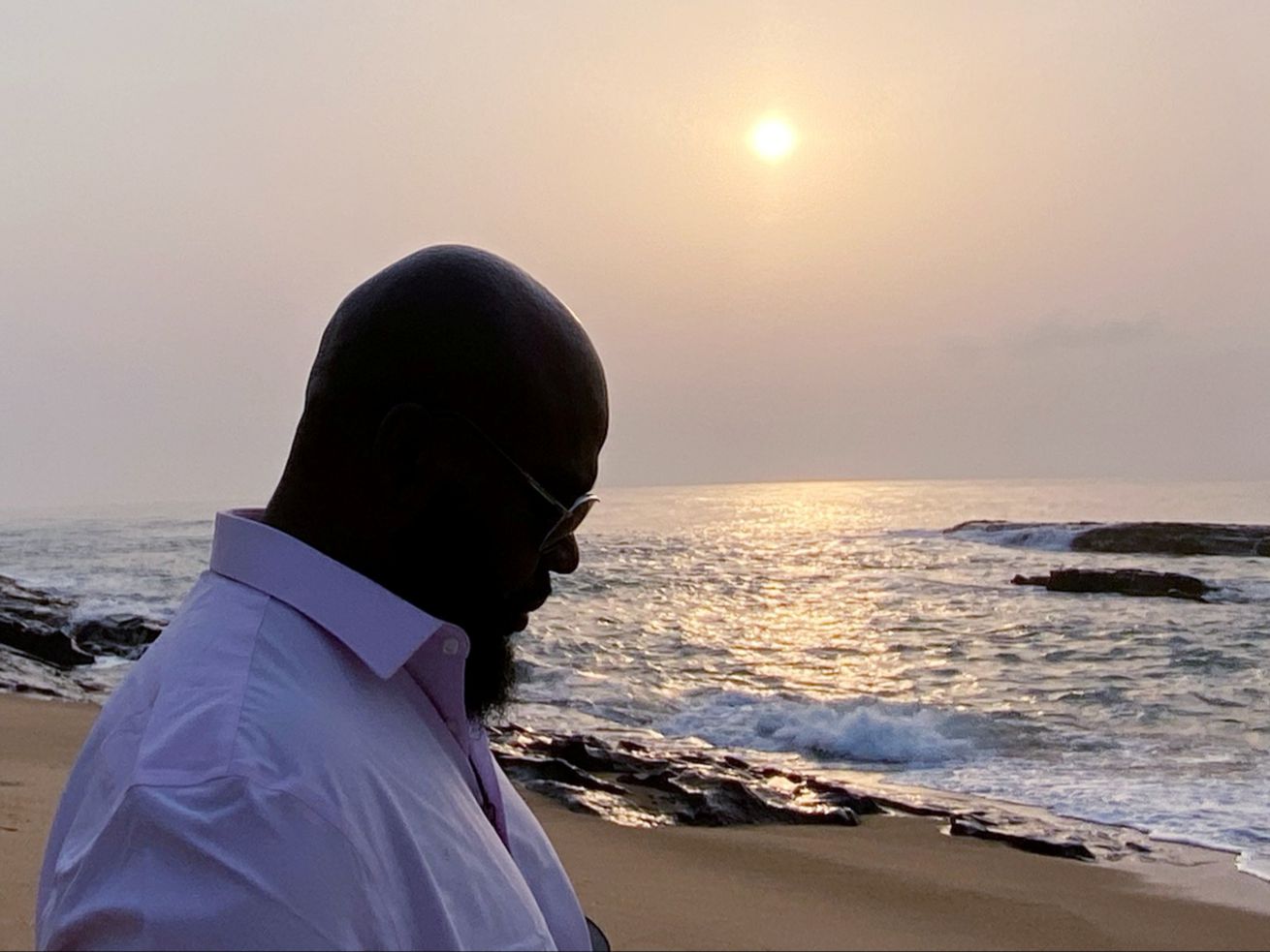 John Fountain at sunrise stands on the coast of the Atlantic Ocean in Ghana. 